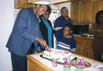 Photograph of a Group of People Standing In a Kitchen, One of Cutting Cake by Las Vegas Chapter of the National Bar Association